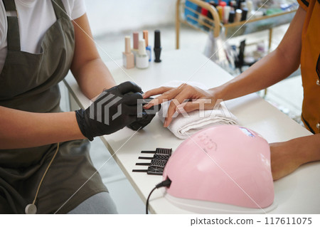 Applying Nail Polish in Modern Nail Salon Setting 117611075