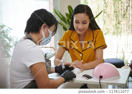 Enjoying Manicure Session While Relaxing at Salon 117611077