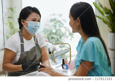Beautician Wearing Mask and Offering Manicure Service 117611101