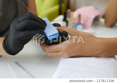 Gloved Hands Holding Nail Buffing Tool for Manicure Gloved Hands Holding Nail Buffing Tool for Manicure 117611106