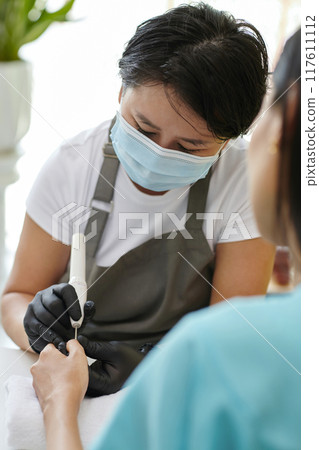 Close-Up of Manicurist Cleaning Woman's Nails at Salon Close-Up of Manicurist Cleaning Woman's Nails at Salon 117611112