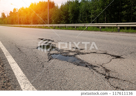 Potholes on bad asphalt road. Closeup 117611136