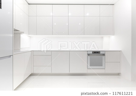 Front view of a modern luxury trendy snow white kitchen with many cabinets Front view of a modern luxury trendy snow white kitchen with many cabinets 117611221