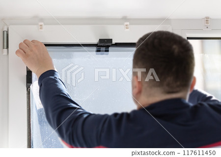 Installation of tinted film. Ultraviolet and energy afficiency concept. Installation of tinted film. Ultraviolet and energy afficiency concept. 117611450