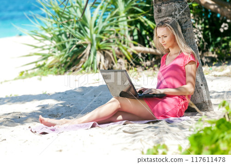 Blond girl with a laptop on tropical beach 117611478
