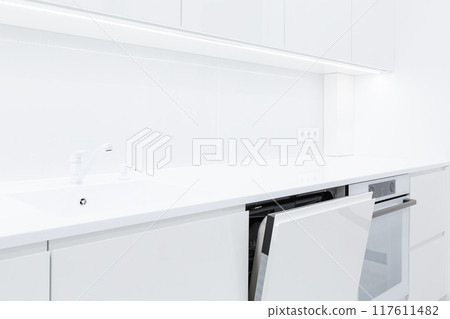 Modern white kitchen interior with acrylic countertop and built in stone sink and opened door of washing machine, 117611482