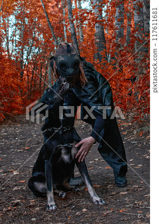 a girl in a bdsm costume and a black mask and with a dog in red forest.an an idea for Halloween. 117611681