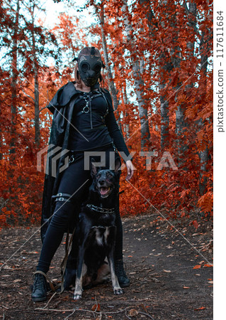 a girl in a bdsm costume and a black mask and with a dog in red forest.an an idea for Halloween. a girl in a bdsm costume and a black mask and with a dog in red forest.an an idea for Halloween. 117611684