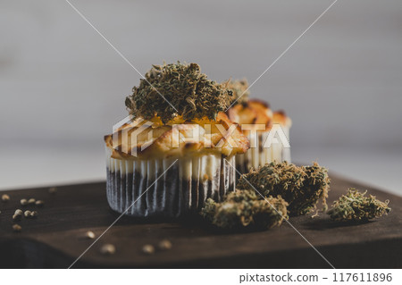 Cake with medical marijuana buds on wooden cutting board, close up Cake with medical marijuana buds on wooden cutting board, close up 117611896