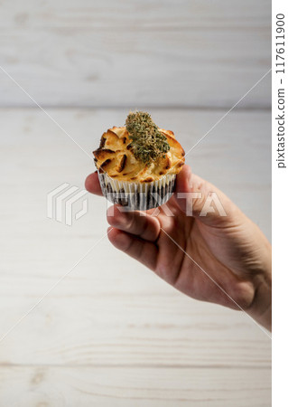 Hand holding cake with medical marijuana buds, close up 117611900