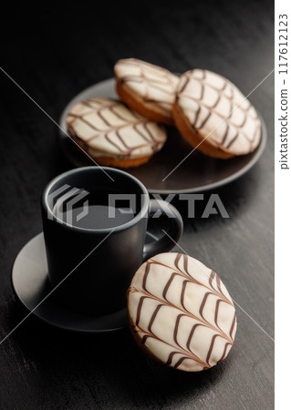 Sweet dessert with sugar coating  and coffee mug on black table. Sweet dessert with sugar coating  and coffee mug on black table. 117612123