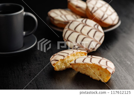 Sweet dessert with sugar coating and coffee mug on black table. Sweet dessert with sugar coating and coffee mug on black table. 117612125