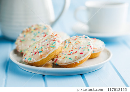 Sweet dessert with sugar coating on plate on blue table. 117612133