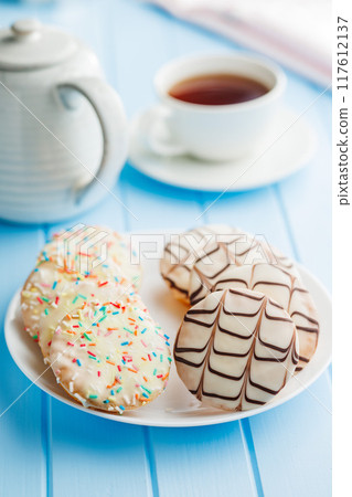 Sweet dessert with sugar coating on plate on blue table. Sweet dessert with sugar coating on plate on blue table. 117612137