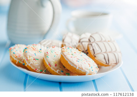 Sweet dessert with sugar coating on plate on blue table. Sweet dessert with sugar coating on plate on blue table. 117612138
