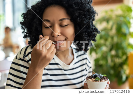 Woman in striped blouse enjoying delicious tiramisu 117612416