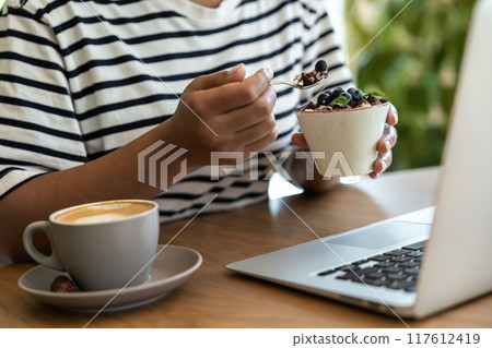 Close up picture of a woman eating tiramisu 117612419