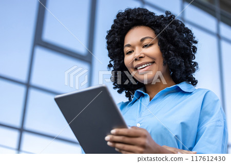 Waist up of a woman with tablet in hands working outdoors 117612430