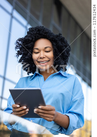 Waist up of a woman with tablet in hands working outdoors Waist up of a woman with tablet in hands working outdoors 117612434