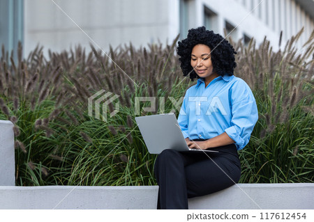 Brunette woman with laptop sitting on a bench and working 117612454