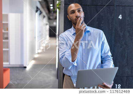 Confident businessman in office hall with laptop 117612469