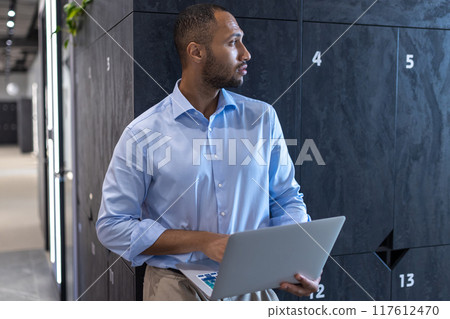 African American businessman working on laptop in office hall 117612470