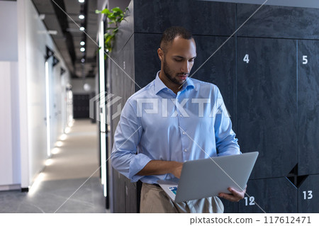 Confident businessman in office hall with laptop 117612471