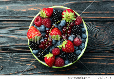 Mix of ripe colorful berries in bowl photography . Blueberry , strawberry , raspberry , blackberry and red currant . Top view 117612503