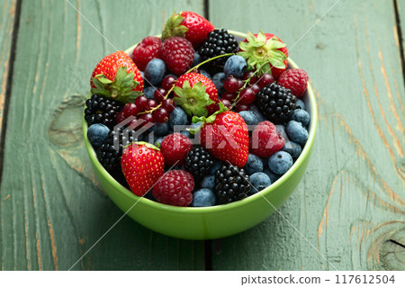 Mix of ripe colorful berries in bowl photography . Blueberry , strawberry , raspberry , blackberry and red currant . Top view 117612504