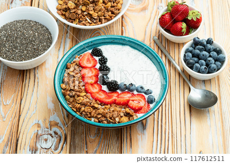 Healthy breakfast . Yogurt with berries ( strawberry , raspberry , blueberry , blackberry ) , granola and chia seeds . Top view 117612511