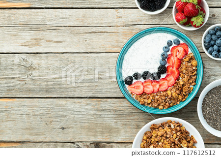 Healthy breakfast . Yogurt with berries ( strawberry , raspberry , blueberry , blackberry ) , granola and chia seeds . Top view 117612512