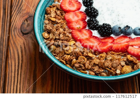 Healthy breakfast . Yogurt with berries ( strawberry , raspberry , blueberry , blackberry ) , granola and chia seeds . Top view 117612517