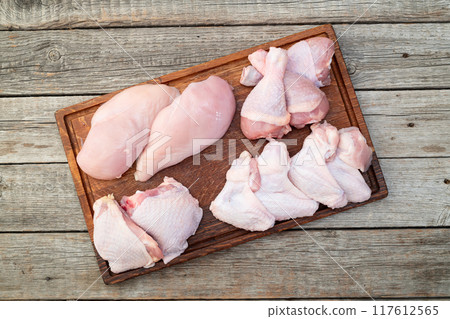 Raw mixed chicken meat parts for cooking on rustic background Raw mixed chicken meat parts for cooking on rustic background 117612565