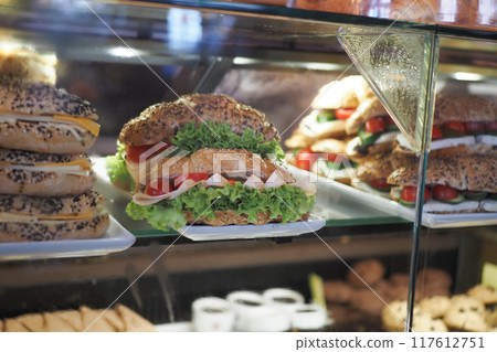 Delicious and Flavorful Sandwiches Alongside Freshly Baked Goods Displayed Neatly in Deli Case 117612751