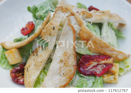 A fresh and appetizing Caesar Salad made with grilled chicken and sundried tomatoes A fresh and appetizing Caesar Salad made with grilled chicken and sundried tomatoes 117612767