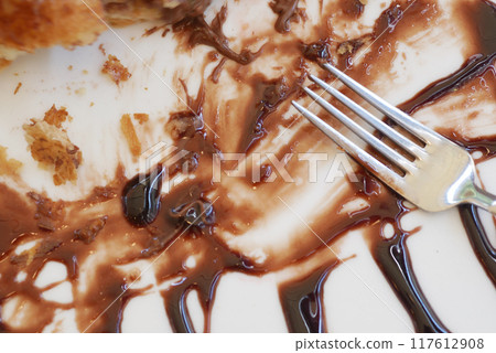 Smeared Chocolate Sauce Creatively Spread on a Plate with a Fork for an Artistic Touch 117612908