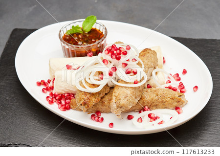 Traditional grilled kebab with pomegranate, onions, spicy sauce for flavorful culinary experience Traditional grilled kebab with pomegranate, onions, spicy sauce for flavorful culinary experience 117613233