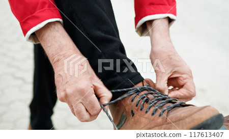 Man Hands Lacing Shoes On A Railing  117613407