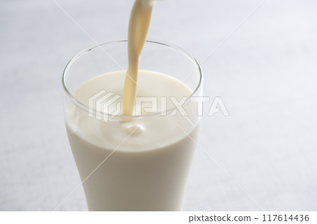Pour soy milk into a glass 117614436