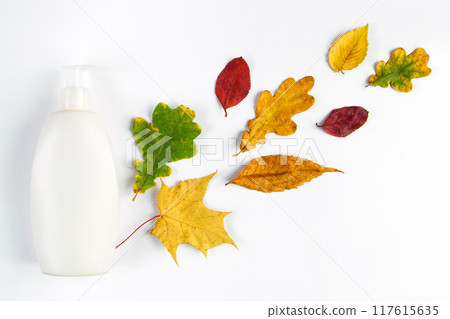 White cosmetic bottle and autumn yellow leaves. Autumn skin care concept. Minimalistic design of eco-friendly cosmetics. Copy space. White cosmetic bottle and autumn yellow leaves. Autumn skin care concept. Minimalistic design of eco-friendly cosmetics. Copy space. 117615635