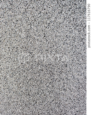 close-up texture shot of a rough, grey surface reminiscent of concrete or stucco. The granular quality and uneven shade variation make it suitable for backgrounds, graphic design 117616790