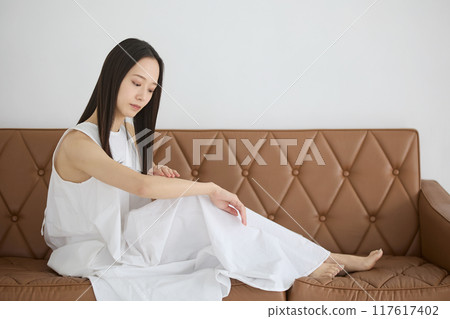 A woman sitting on a sofa and doing skin care A woman sitting on a sofa and doing skin care 117617402