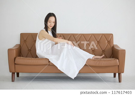 A woman sitting on a sofa and doing skin care A woman sitting on a sofa and doing skin care 117617403