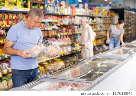 Mature man shopping in supermarket, choosing frozen convenience food 117618045