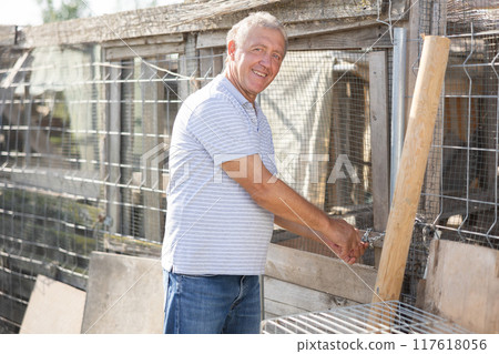 Elderly man posing near hen house Elderly man posing near hen house 117618056