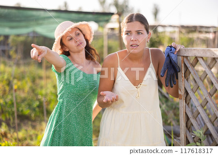 Two young women neighbors quarrel and swear near trellis Two young women neighbors quarrel and swear near trellis 117618317