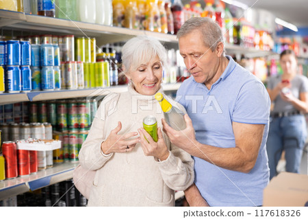 Elderly couple choosing carbonated drinks together in aluminum cans in the grocery section of supermarket 117618326