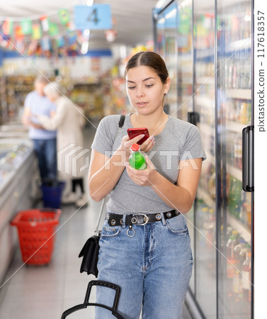 Woman purchaser scanning label of cool drink by phone 117618357