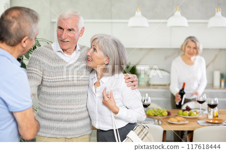 In home, mature man shake hands with couple, say hello, inviting to home family event 117618444