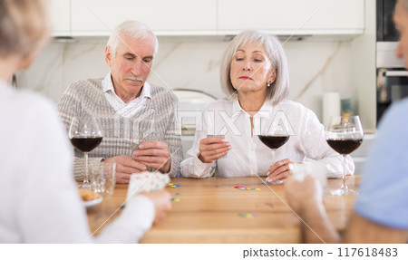 Two mature married couples playing card game poker 117618483